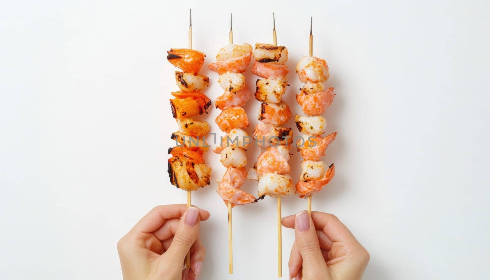Woman hands holding four grilled shrimps and scallops skewers with copy space