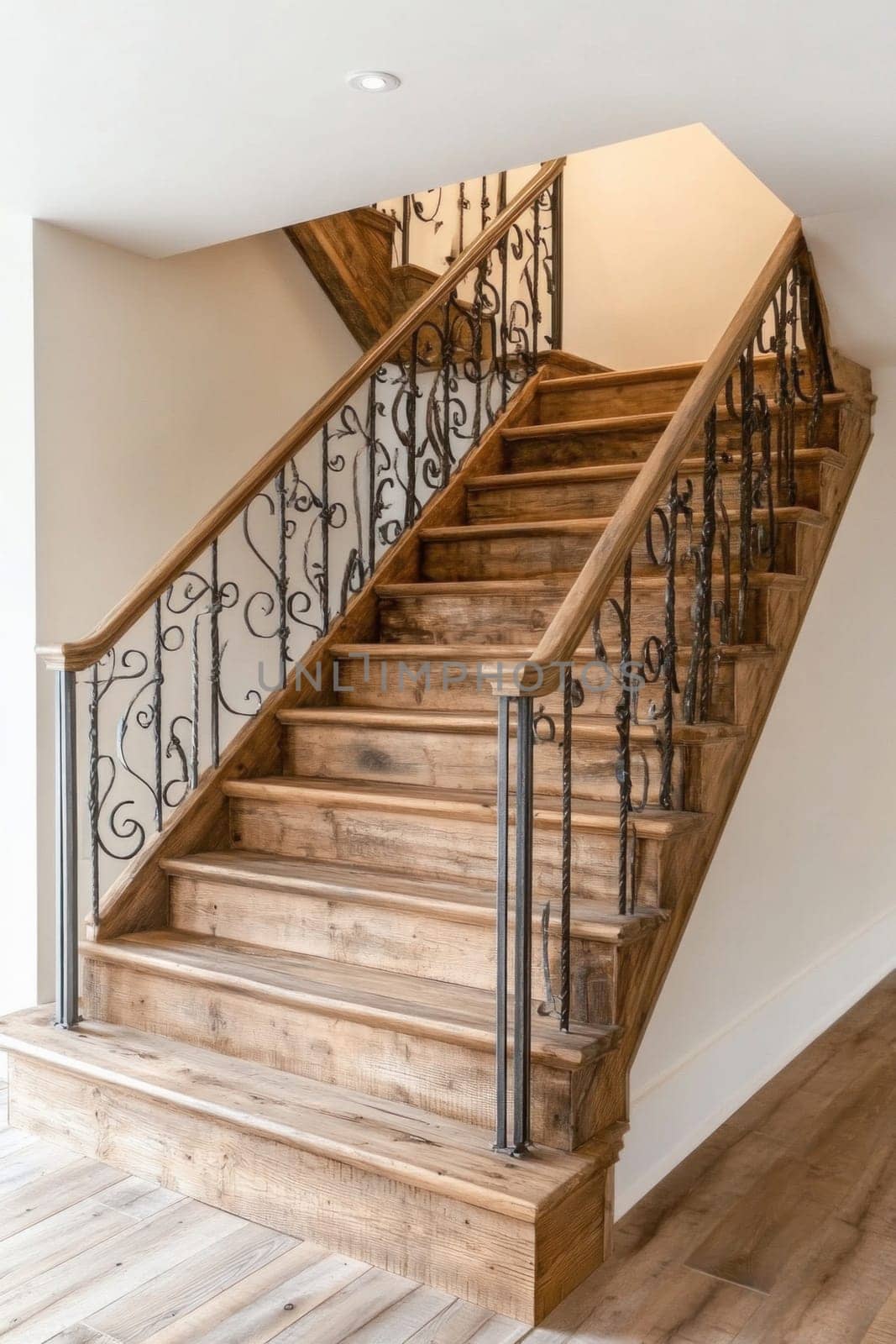Empty wooden staircase with wrought iron railing is illuminated by a ceiling light