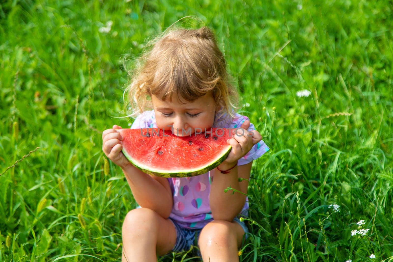 Child eats watermelon in summer. Selective focus. Kid.