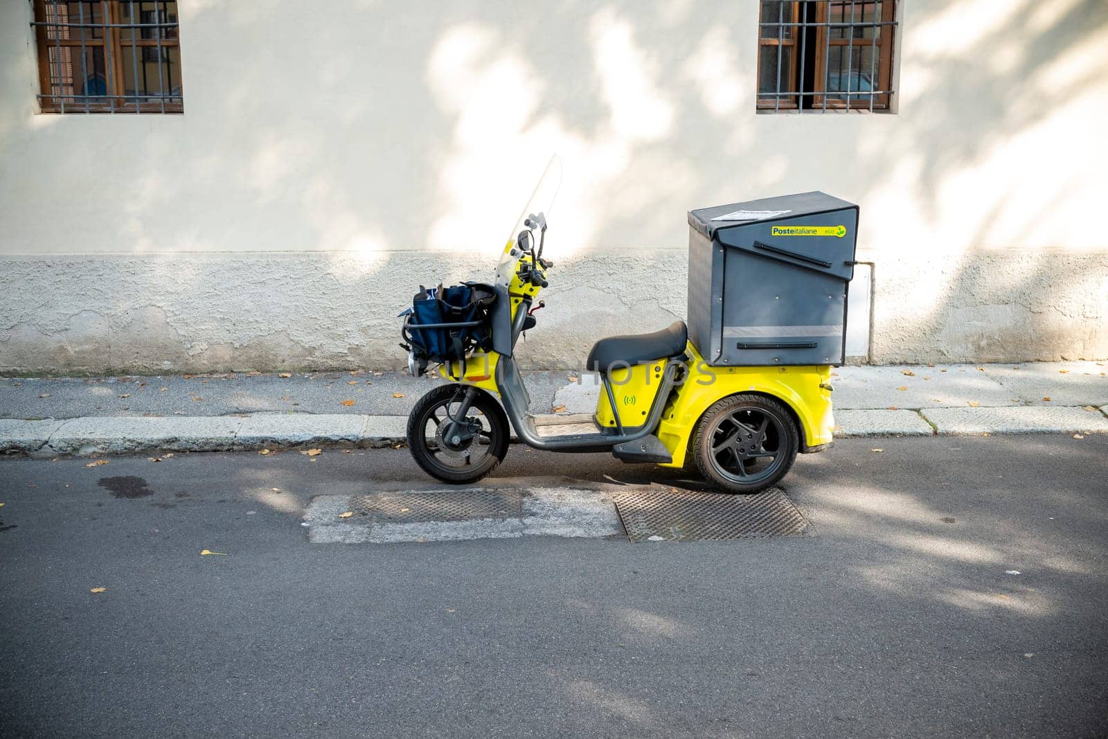 Cremona, Lombardy, Italy October 15th 2024 Poste Italiane Yellow three wheeled motorbike parked on the sidewalk delivering mail and parcels for the postal service in an urban setting