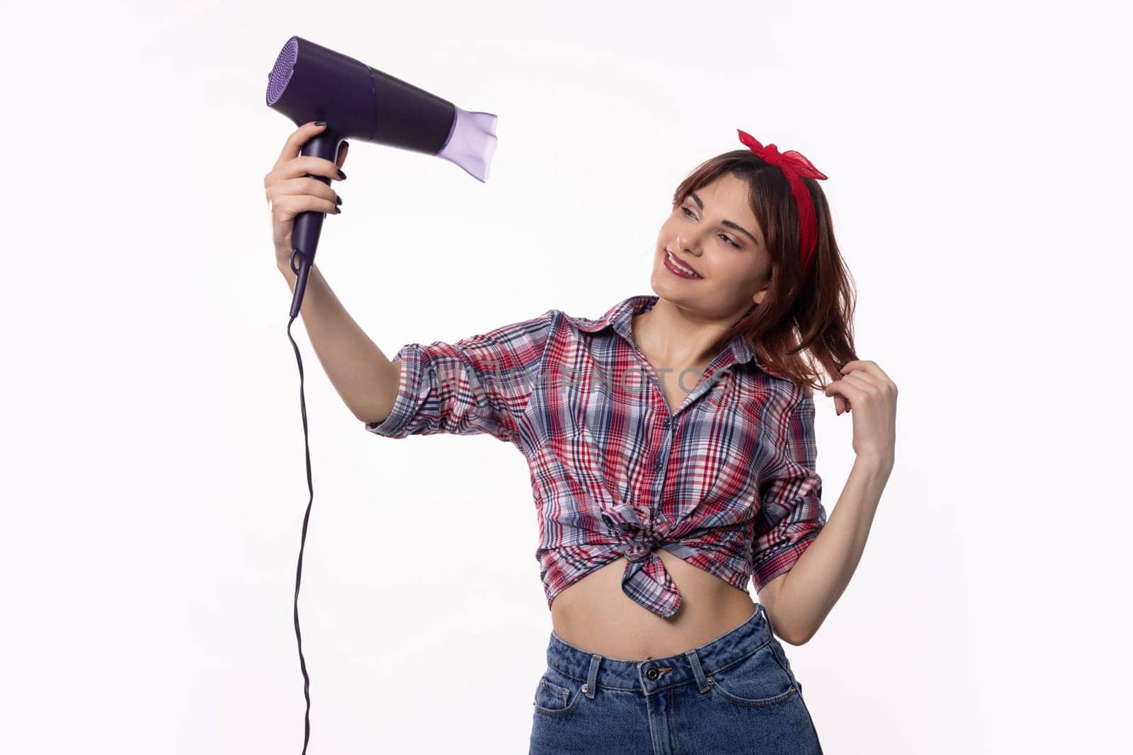 A stylish and fashionable young woman is playfully using a hair dryer, which showcases her unique sense of style