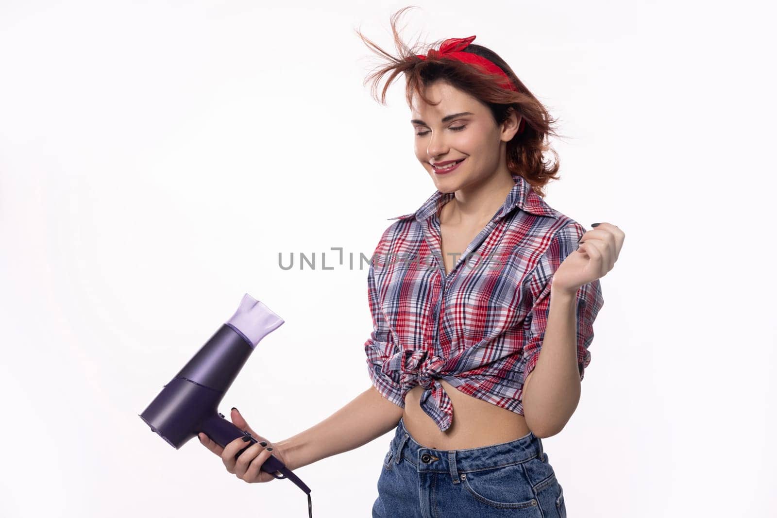 In a cheerful and lively atmosphere, a joyful woman enjoys styling her hair using a dryer with great delight