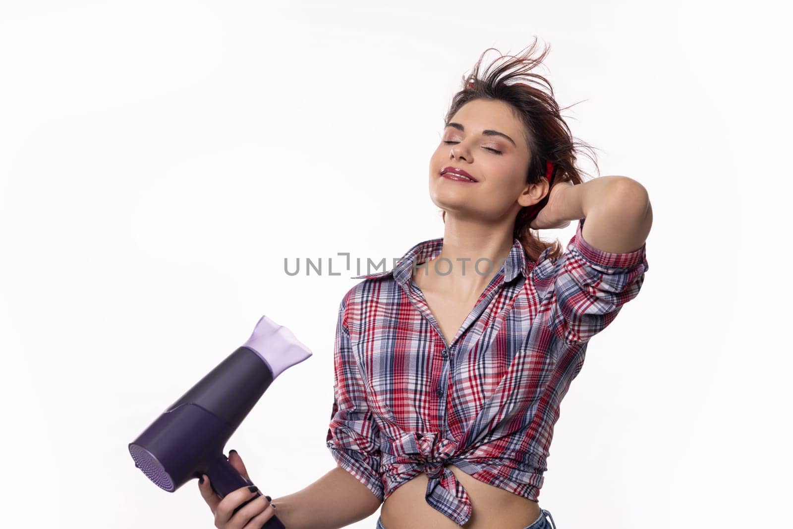 A confidently poised woman happily using a hair dryer, joyfully showcasing beautiful hair styling trends