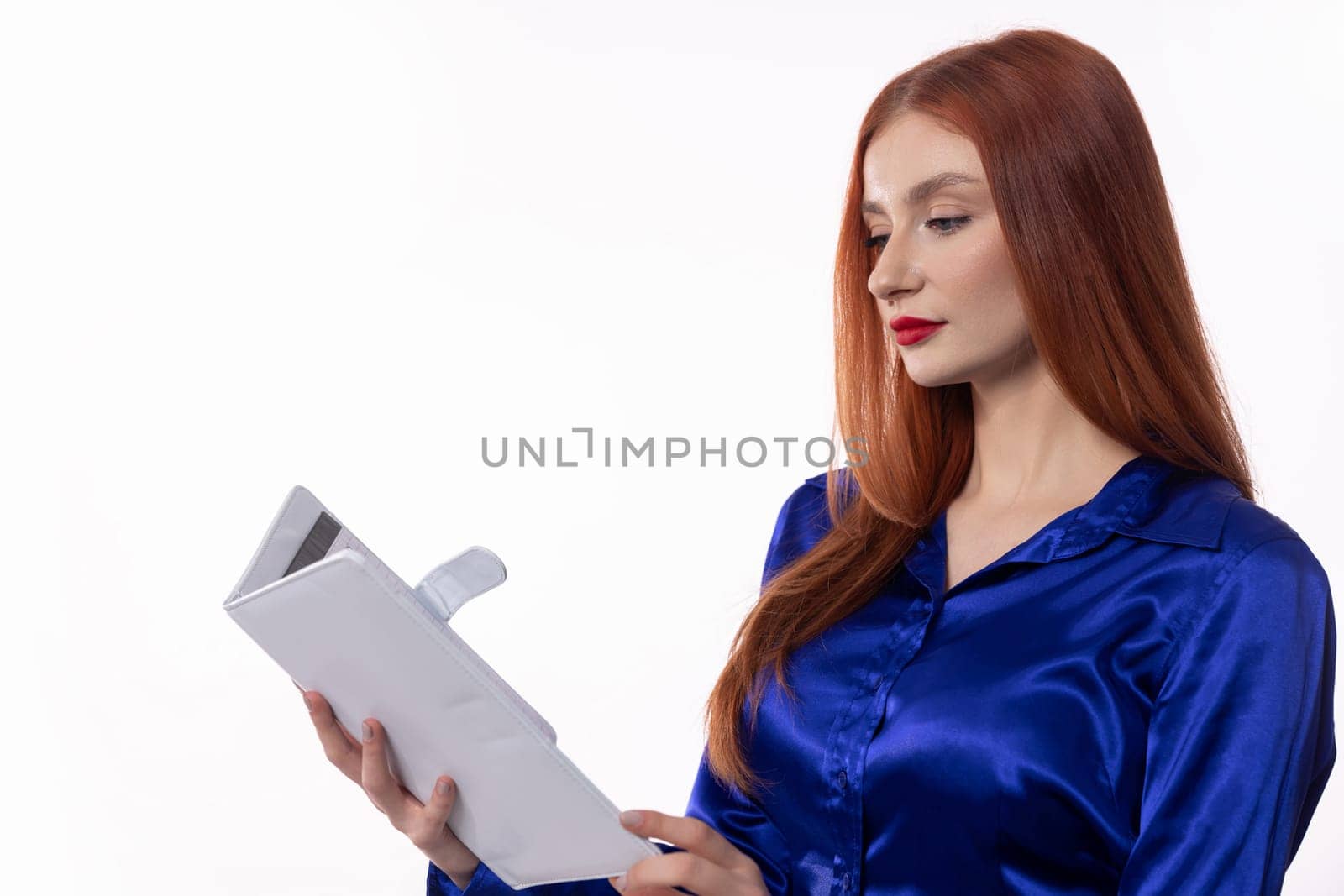 A stylish and sophisticated woman dressed in elegant blue satin attire is deeply focused while reading a document