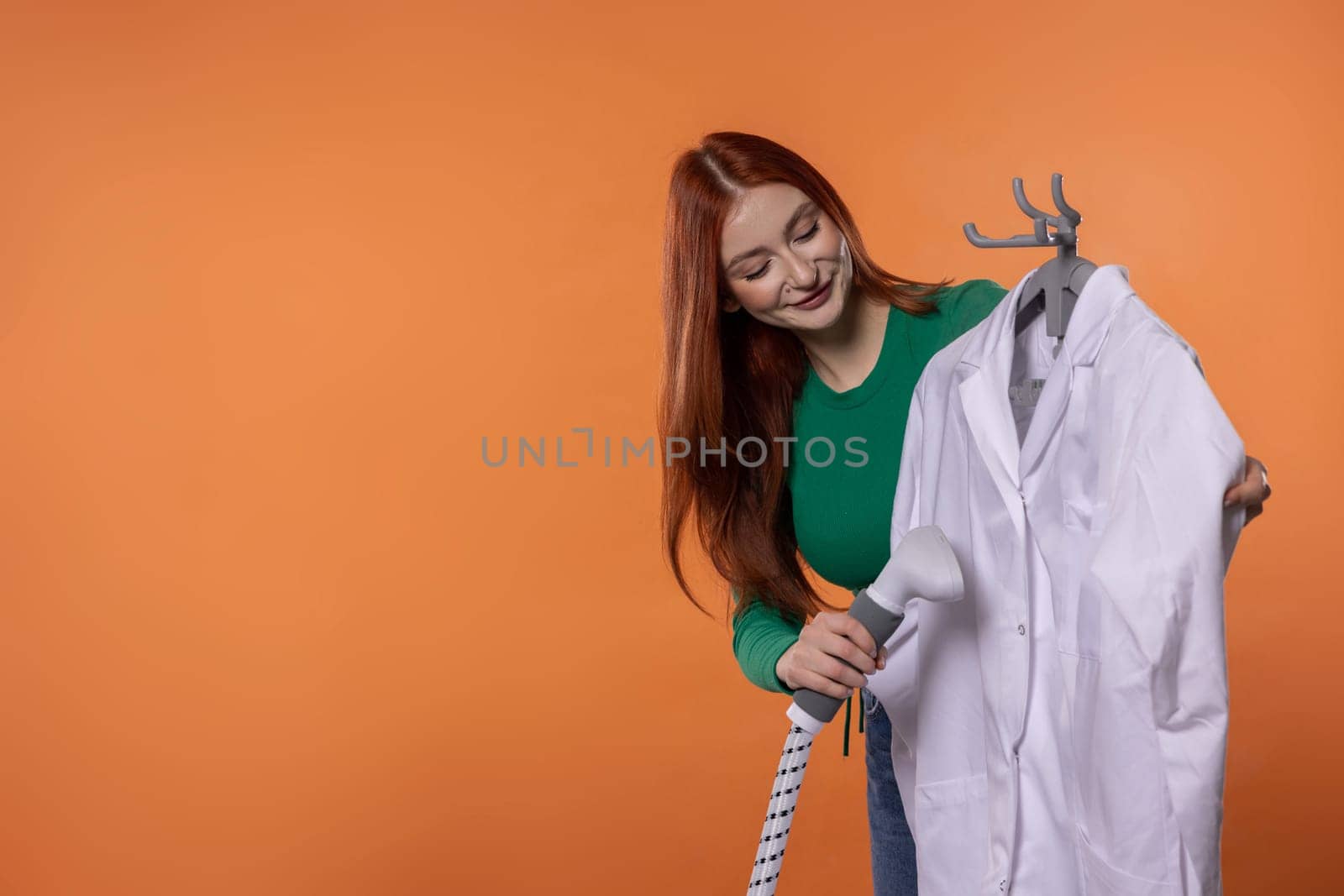 A young woman smiles while preparing a clean white lab coat, showing her care for professional attire and detail