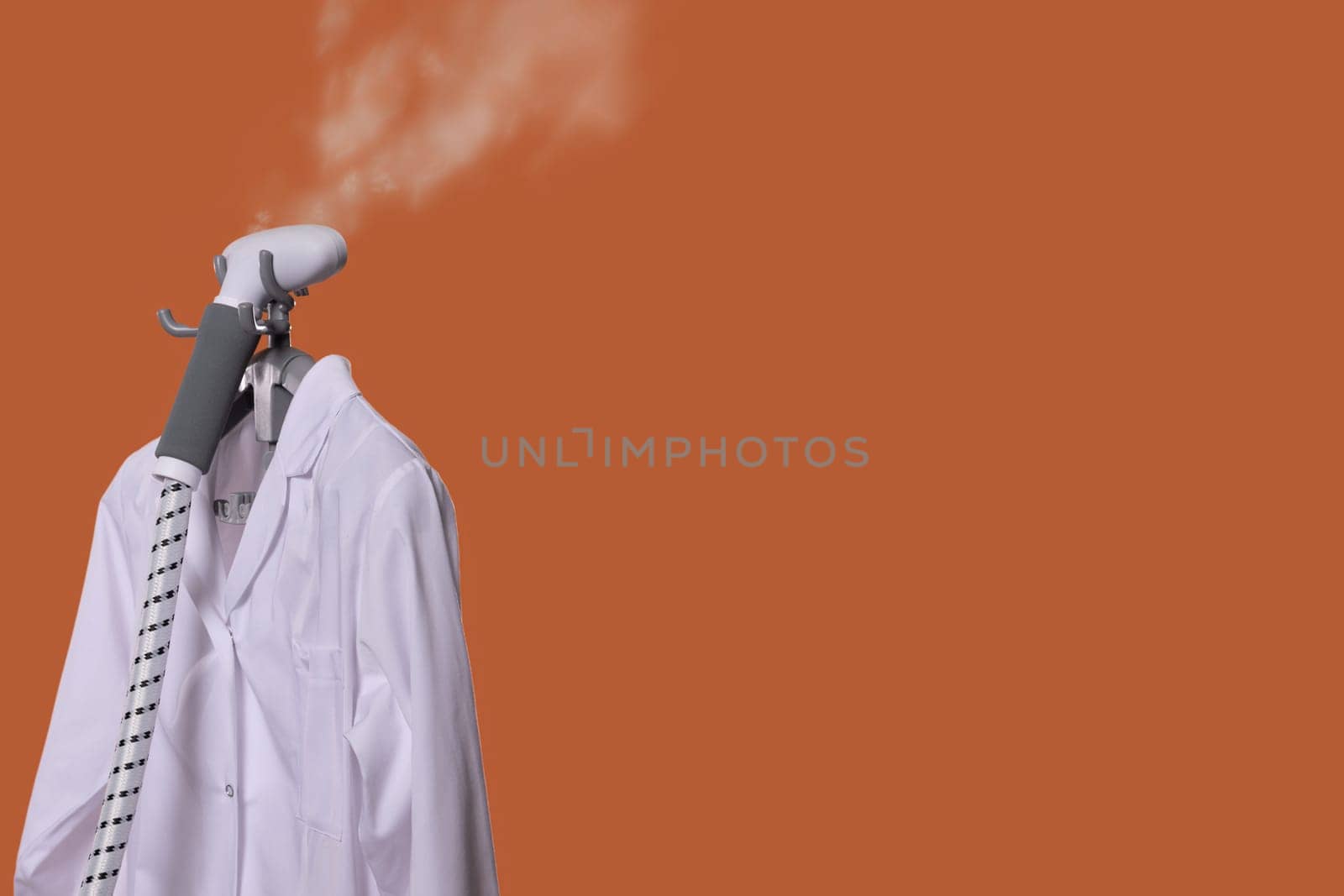 Effortlessly steam and smooth out a brilliant white shirt using a steam iron set against an inviting orange background