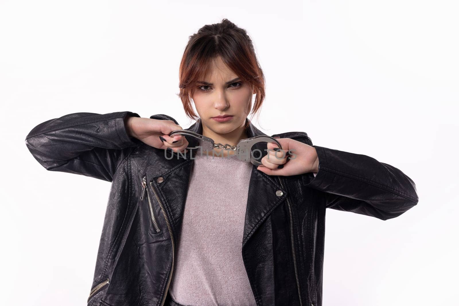 A confident young woman striking a fashionable pose in a black leather jacket, showcasing modern style.