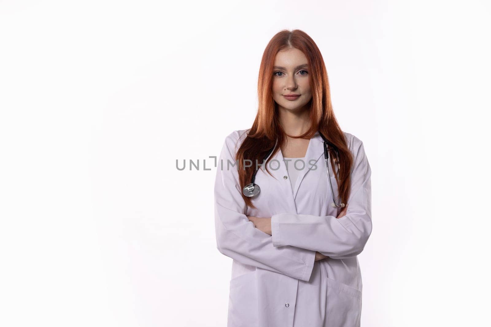 A skilled female doctor stands confidently with her arms crossed in a lab coat and stethoscope around her neck