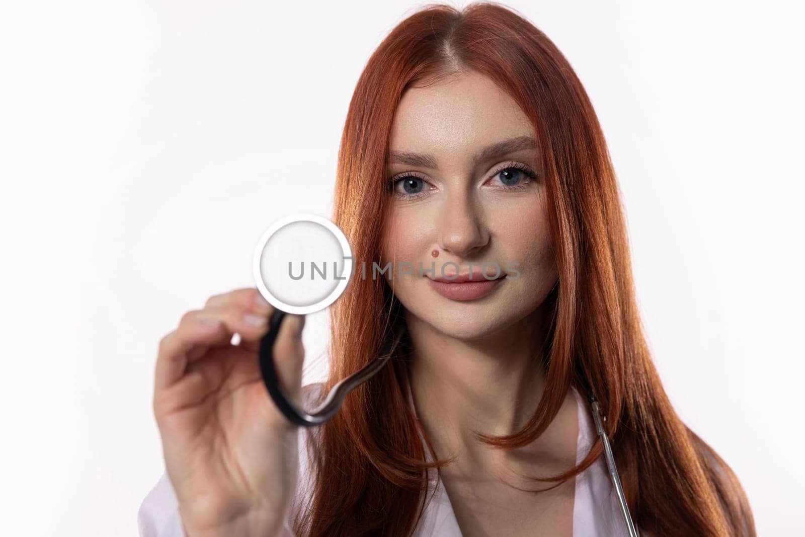 A confident young female doctor with red hair is proudly showcasing her stethoscope, exuding professionalism