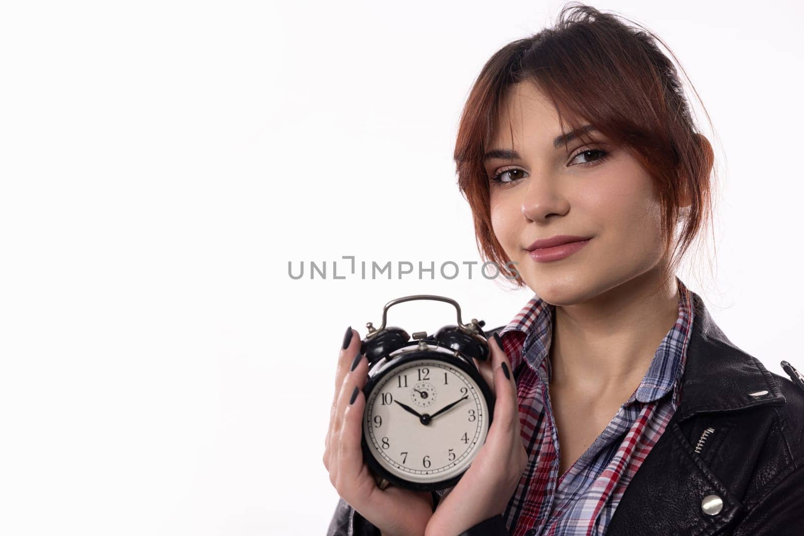 A stylish young woman poses with an alarm clock, emphasizing the importance of time awareness and productivity