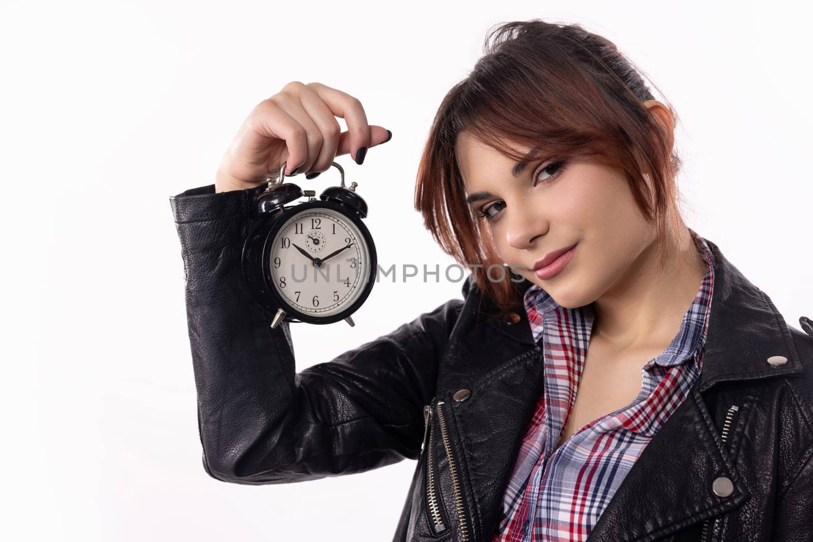 A fashionable woman stands elegantly with a classic alarm clock, showcasing a blend of style and time management