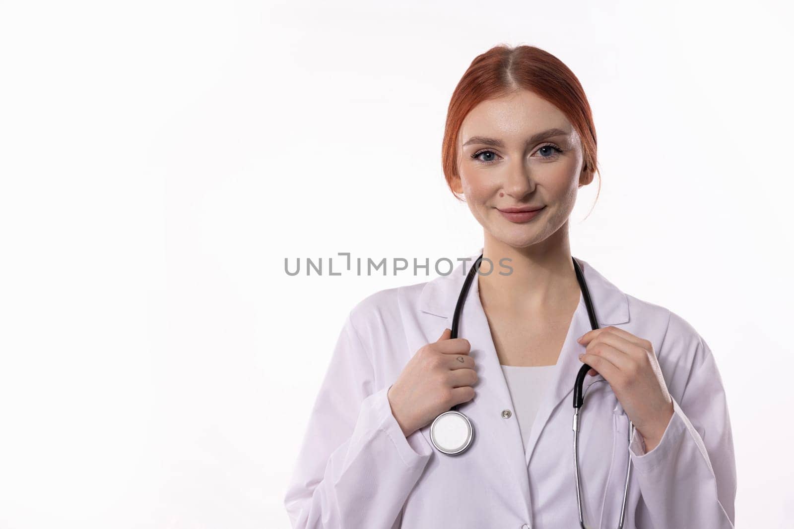 A cheerful female doctor wearing a white coat confidently demonstrates her professionalism and pride in her work