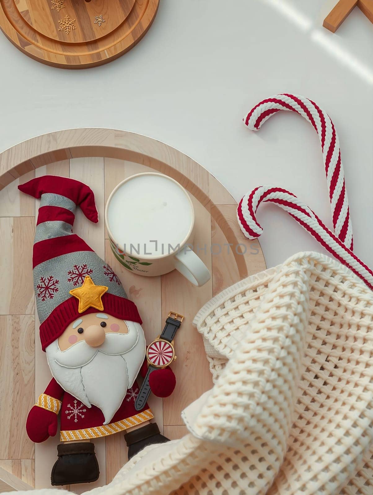 The image presents a festive scene set on a white surface. Dominating the center is a charming gnome figurine, adorned in a vibrant red and gold outfit, complete with a matching hat and a white beard. The gnome is holding a white mug, which is filled with a white liquid, possibly milk. To the right of the gnome, there are two candy canes, one red and one white, adding a pop of color to the scene. The background is blurred, drawing focus to the gnome and its surroundings.