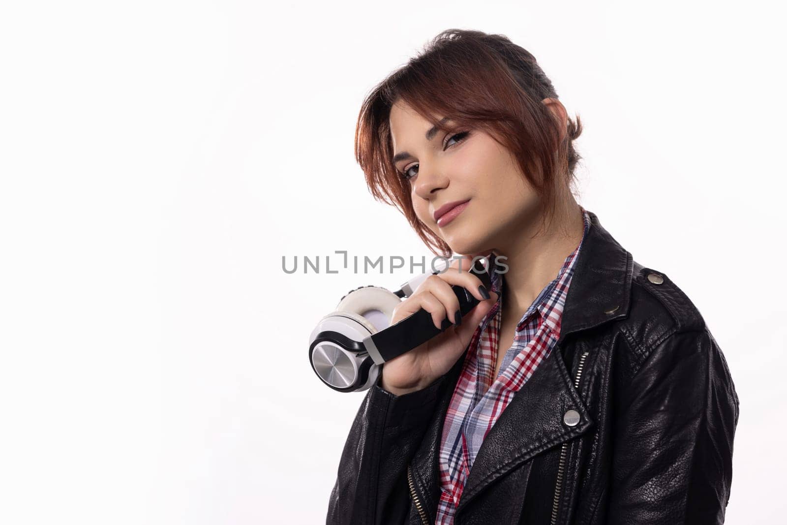 A chic and stylish young woman confidently poses outdoors while holding a flashlight in her leather jacket
