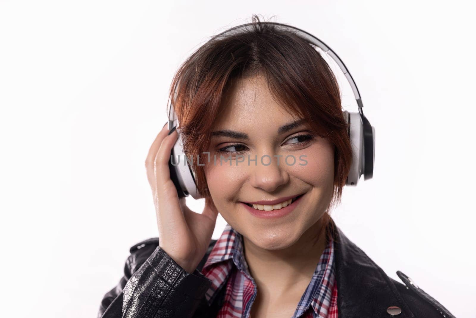 A cheerful young woman is joyfully listening to music with her headphones on, radiating pure happiness all around