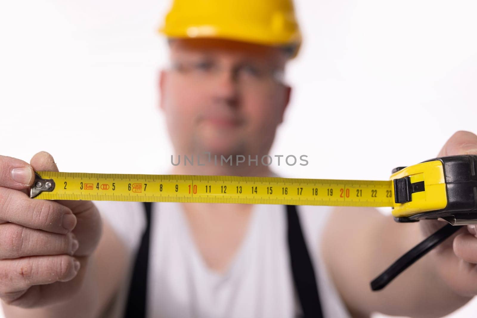 A construction worker measures with a tape, emphasizing the importance of precision in building projects