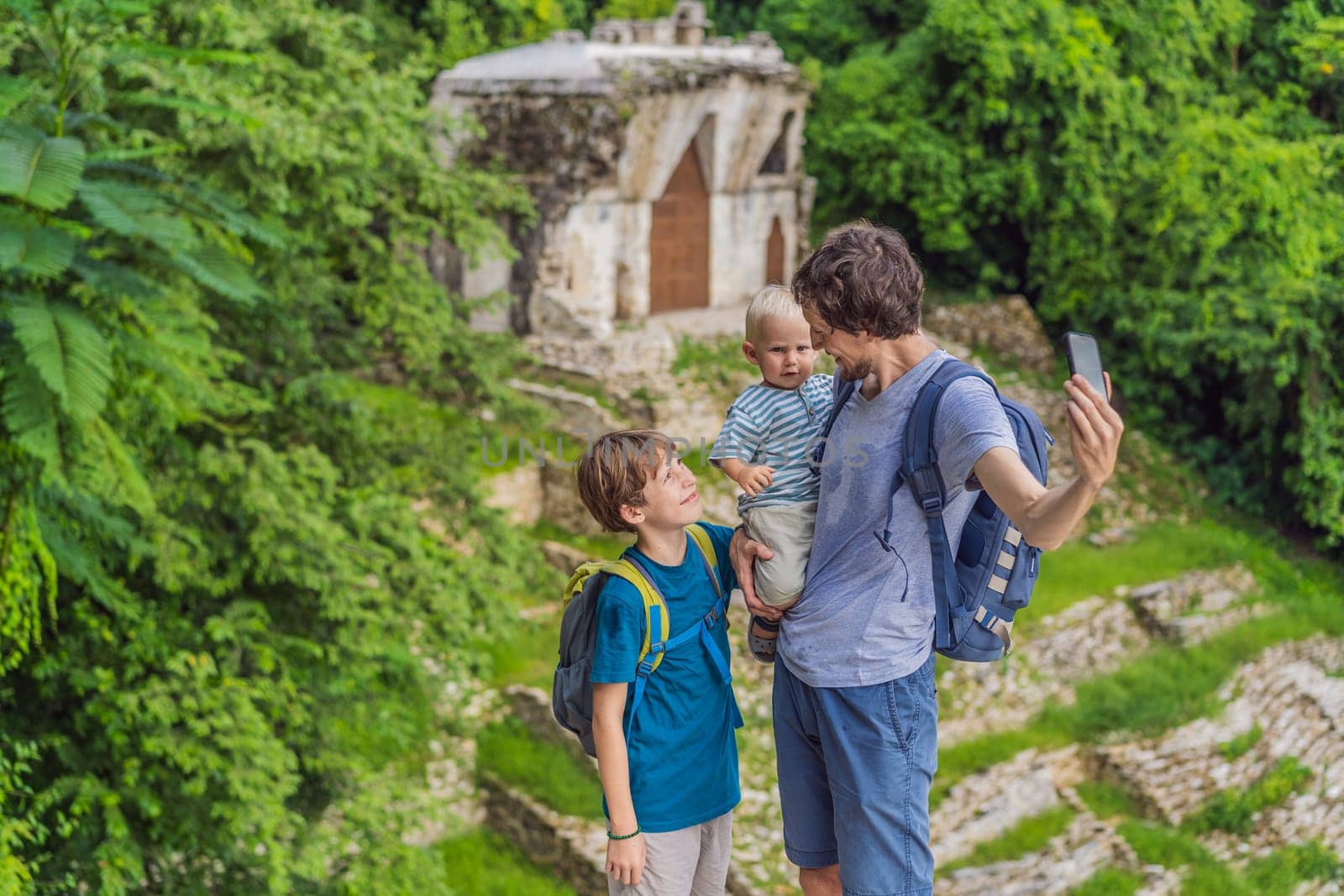 Father with his toddler and teenage sons exploring the ancient pyramids of Palenque, Mexico, surrounded by dense jungle. Cultural heritage and adventure travel concept.