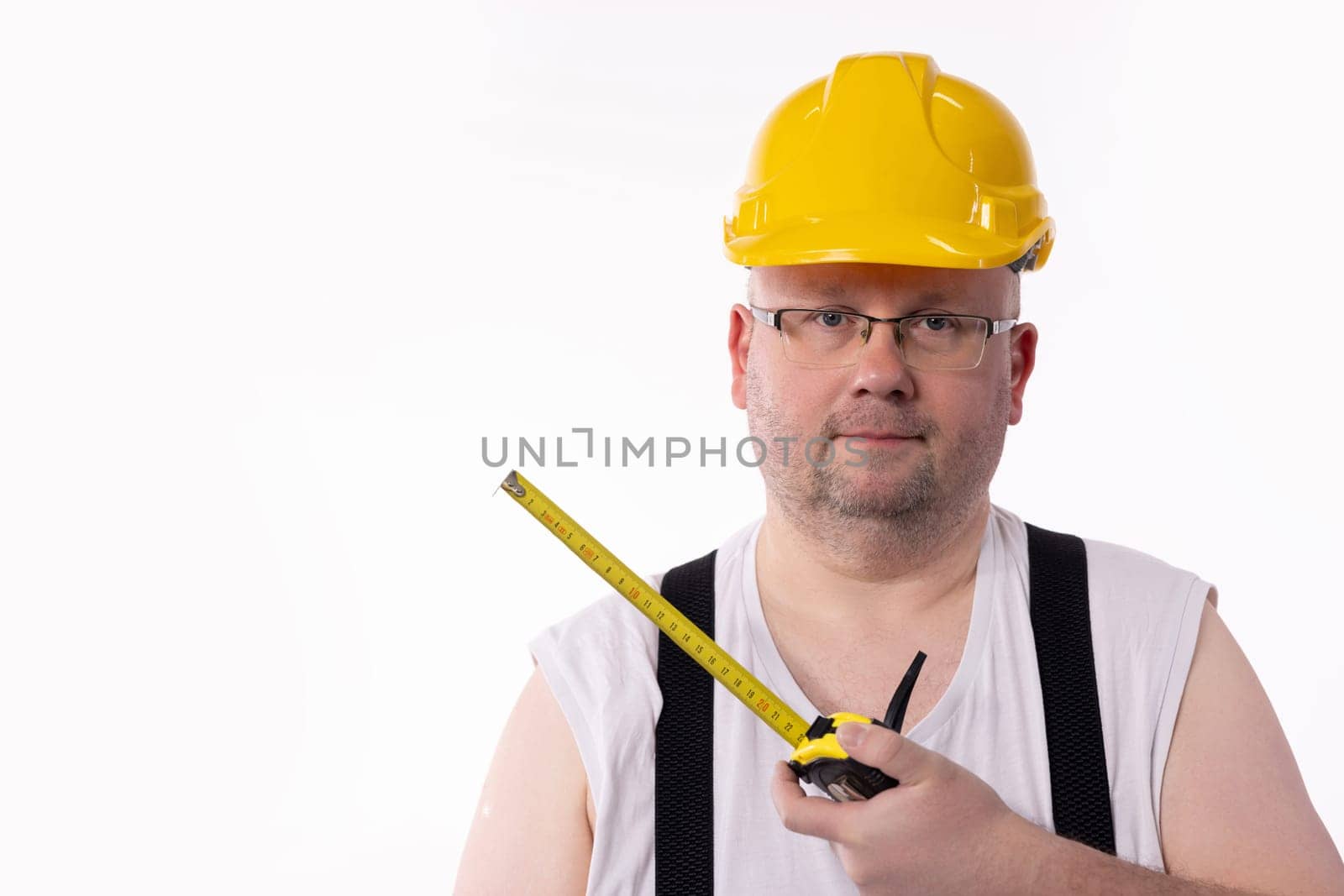 A diligent construction worker wearing a bright yellow hard hat is holding a measuring tape, poised for a new project