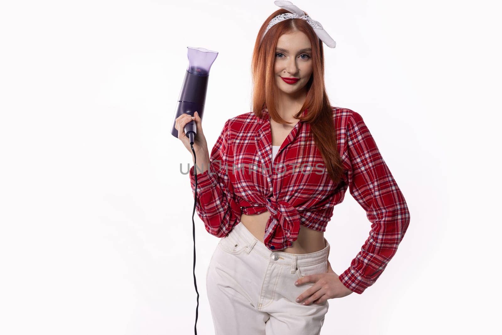 A vibrant woman wearing a red plaid shirt confidently holds a stylish blender, exuding both confidence and creativity