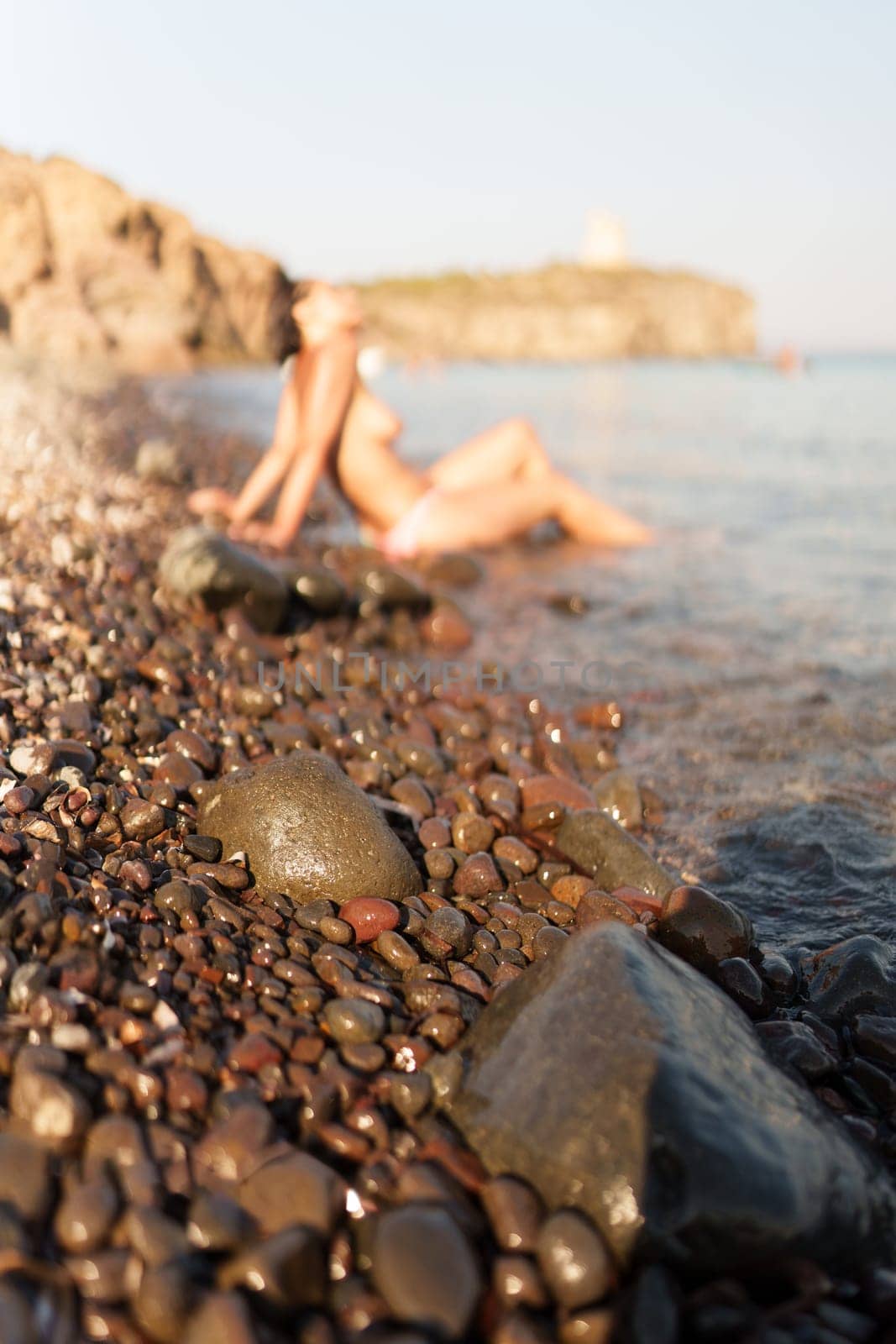Woman sunbathing topless on the seashore. Sardinia, Italy