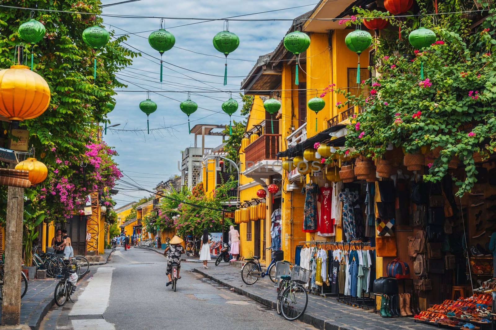 Street in old town in Hoi An city with traditional ancient yellow houses and buildings in summer in day. Hoi An, Vietnam - September 12, 2024