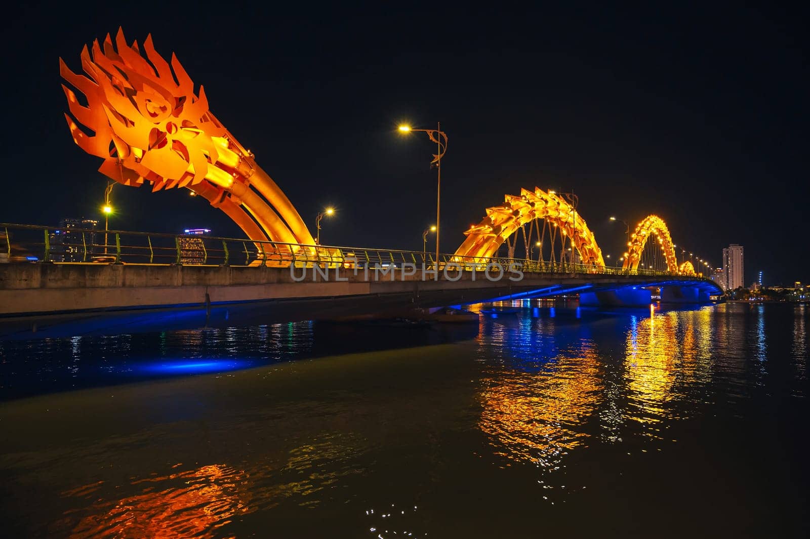 Dragon Bridge over the Han River is a famous landmark in Da Nang in Vietnam at night with a golden illuminated