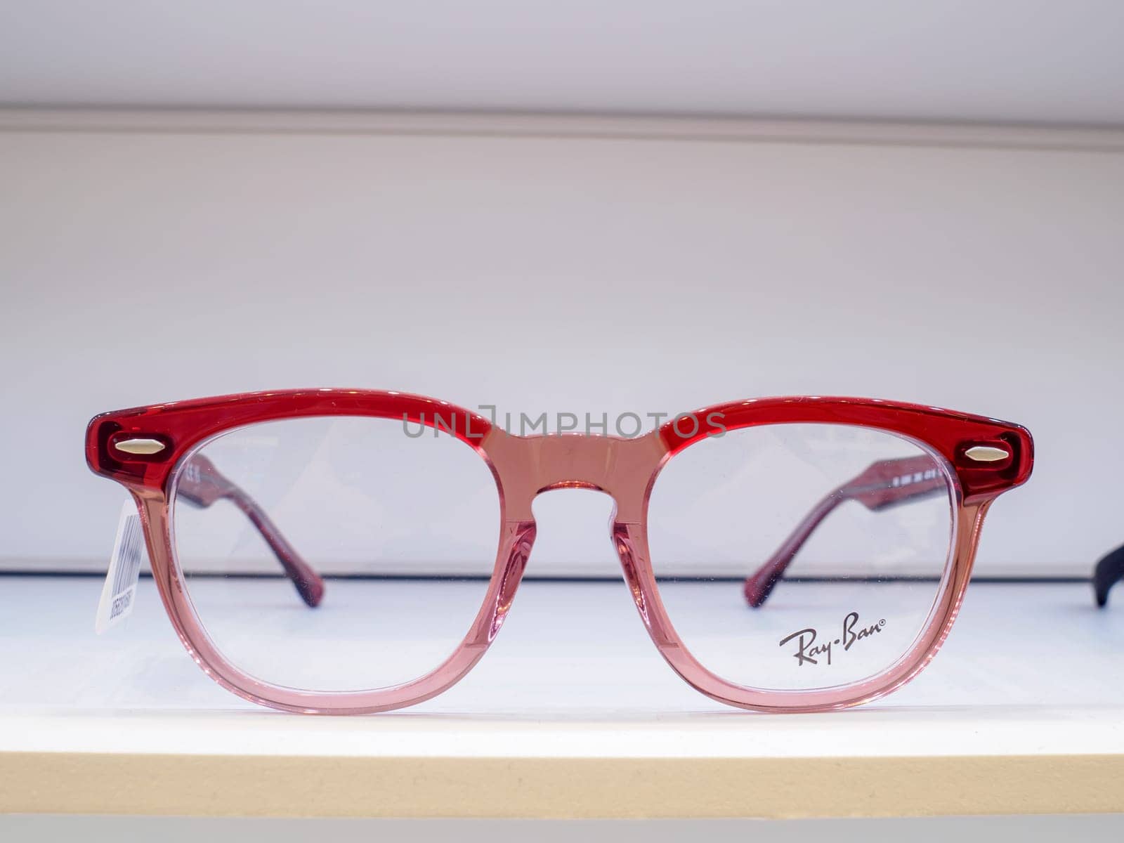 Pair of red eyeglasses sits on a white shelf, ready for a customer to try on and find the perfect frames for their vision needs