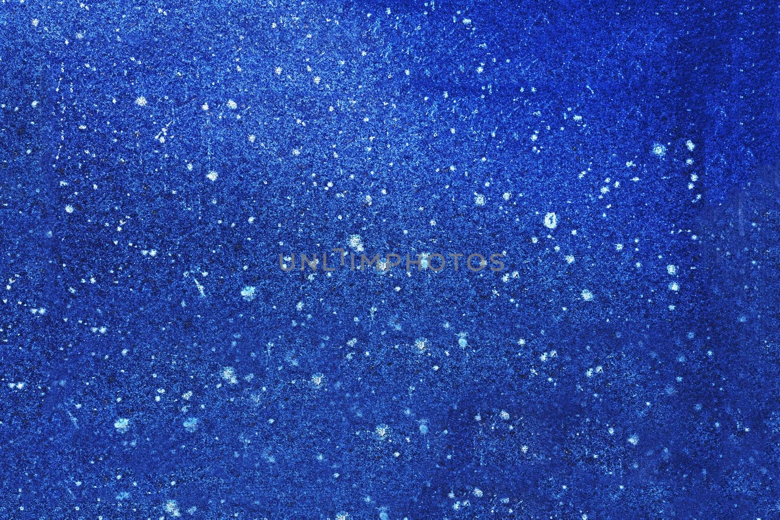 The surface of an old, spotted, uneven stone wall painted blue.