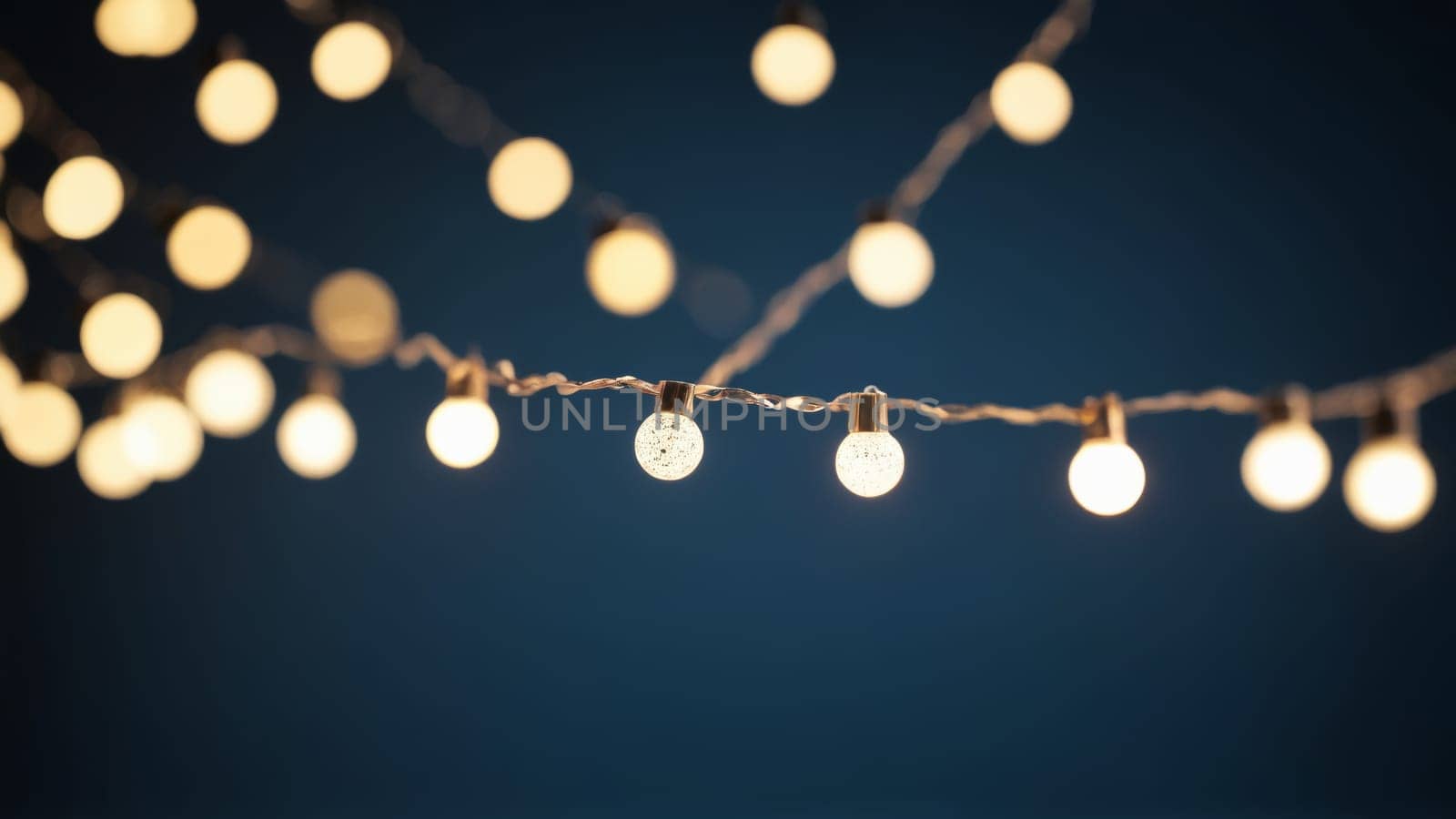 Glowing orbs hang delicately above, casting a warm light over a cozy outdoor setting filled with laughter and joy as night falls.