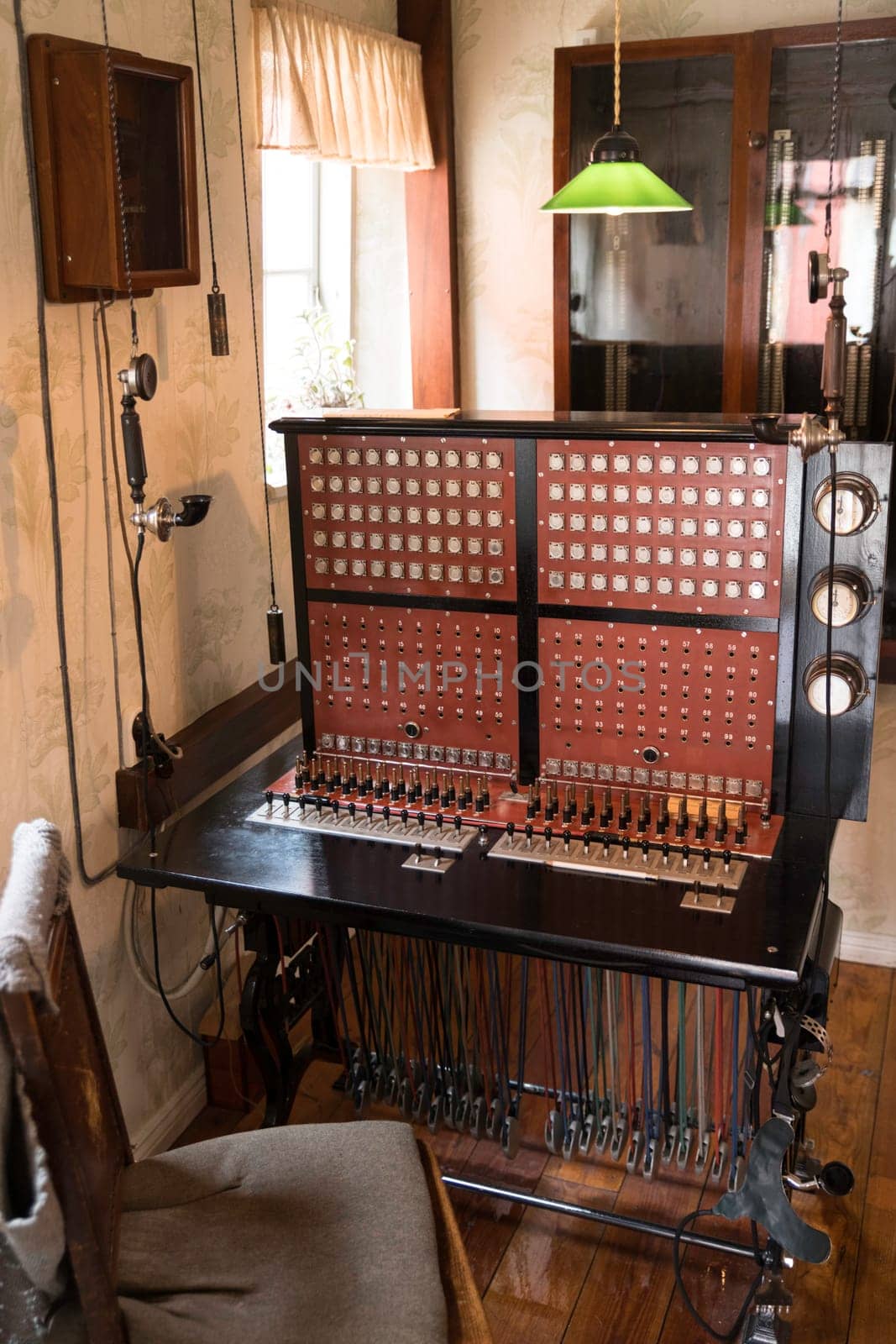 A classic vintage telephone switchboard, showcasing the history of communication technology. Set in an authentic period interior with wood furnishings and a green lamp