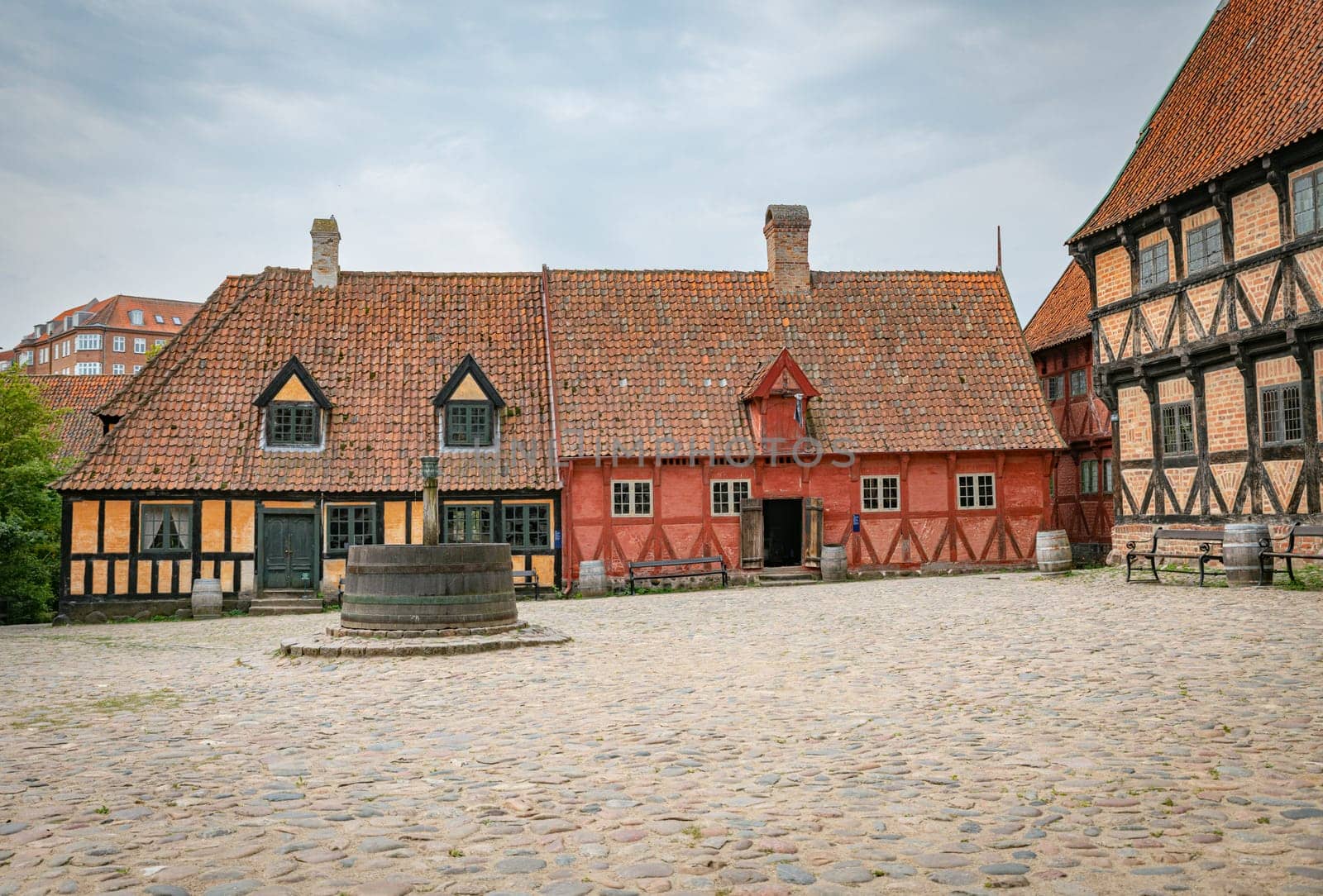 arhus,denmark,An old European courtyard featuring traditional half-timbered buildings and a stone fountain, evoking historical charm and cultural heritage from a bygone era.