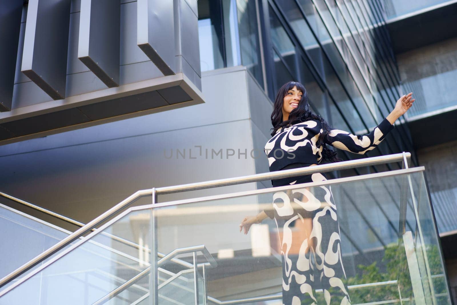 Low angle view photo of a female caucasian cool artist dancing energetically from the stairs of a modern building