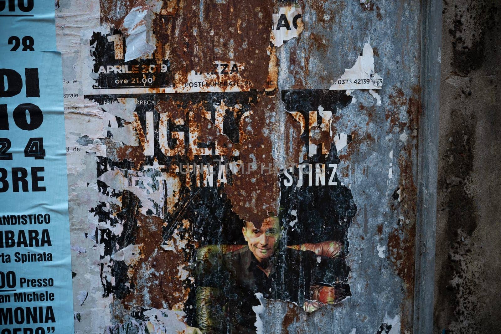 Cremona, Lombardy, Italy October 15th 2024 Weathered advertising posters are peeling from a rusty metal surface, creating an abstract composition