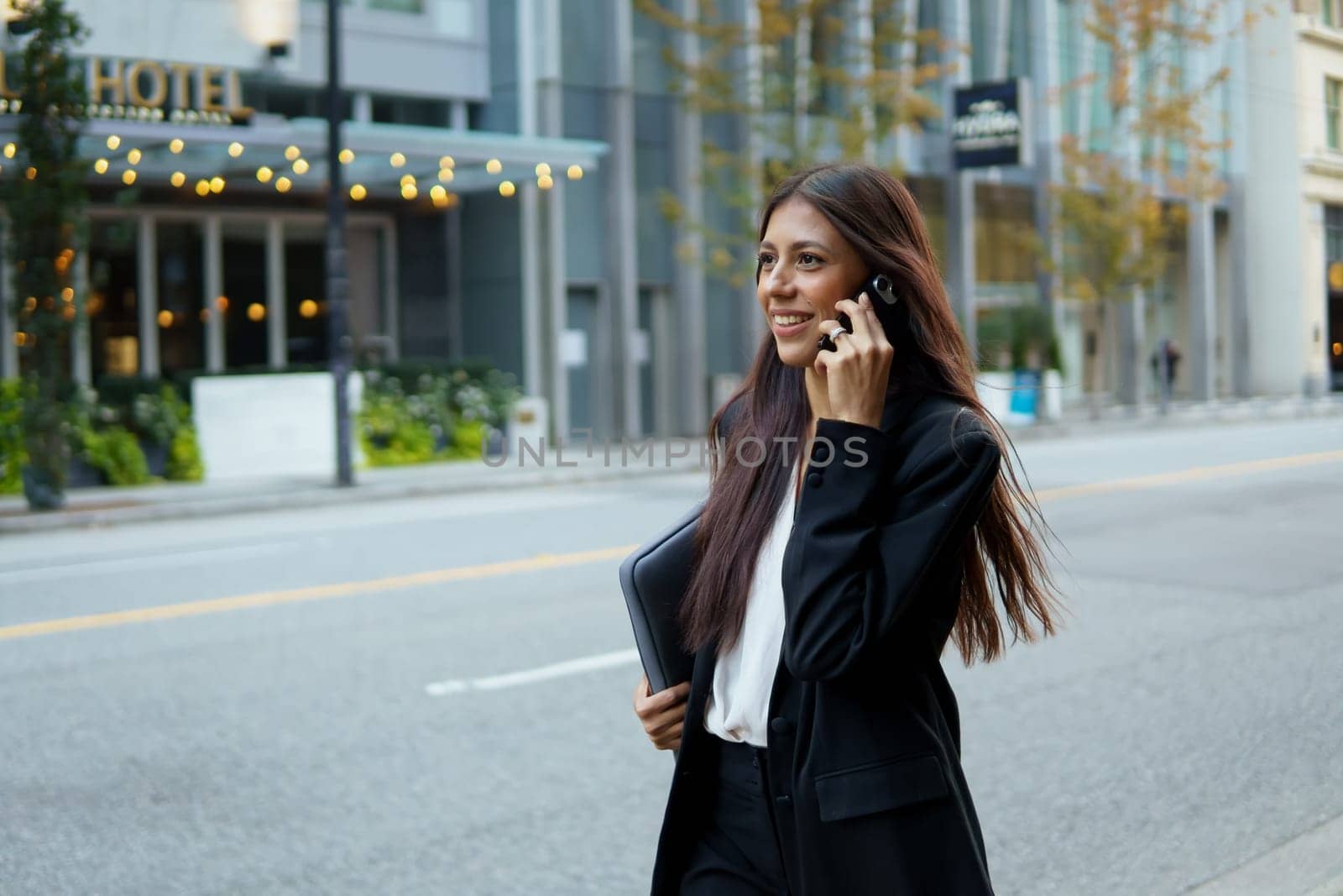 A woman is talking on her cell phone while walking down a street.