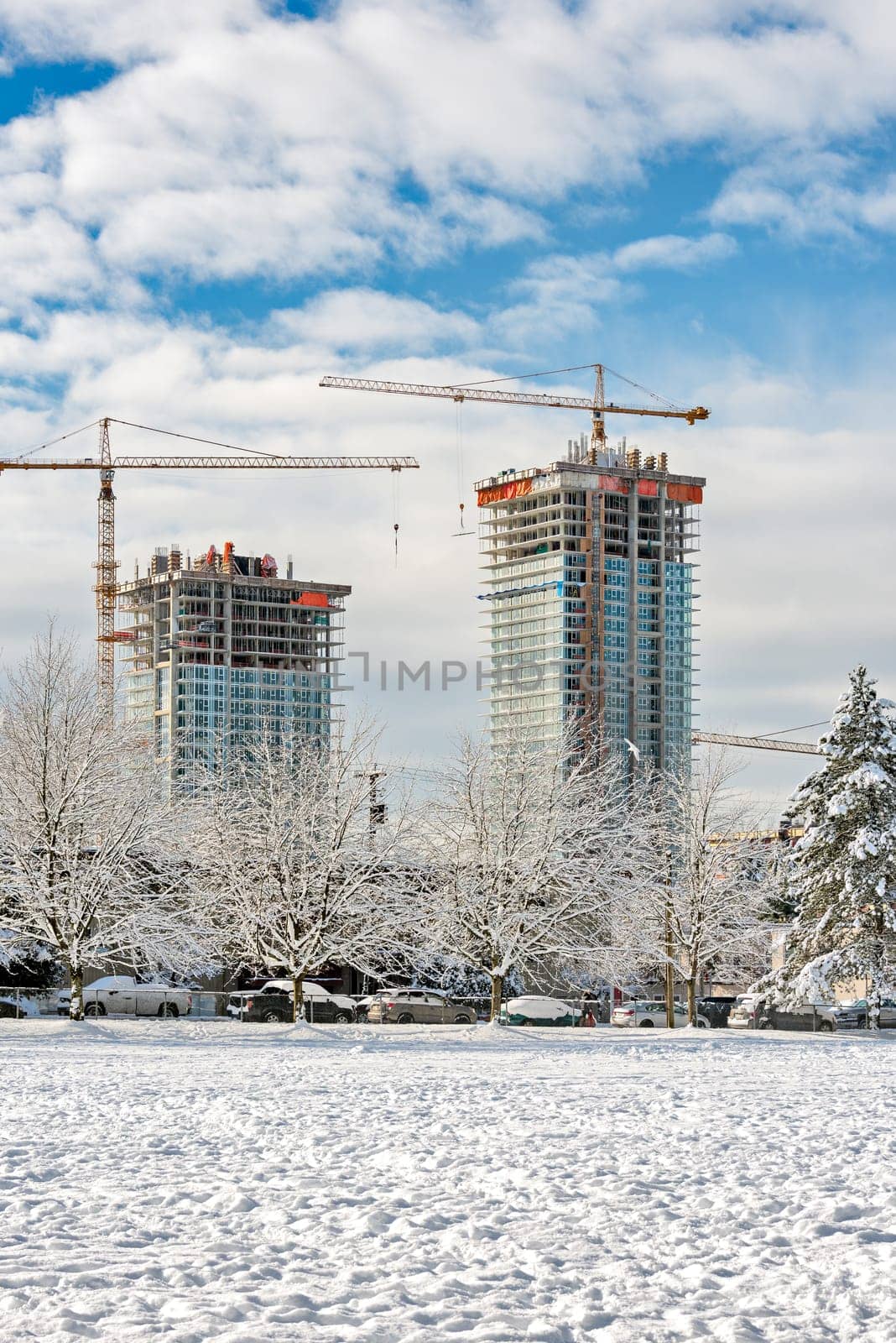 New high-rise residential buildings under construction on bright winter day.