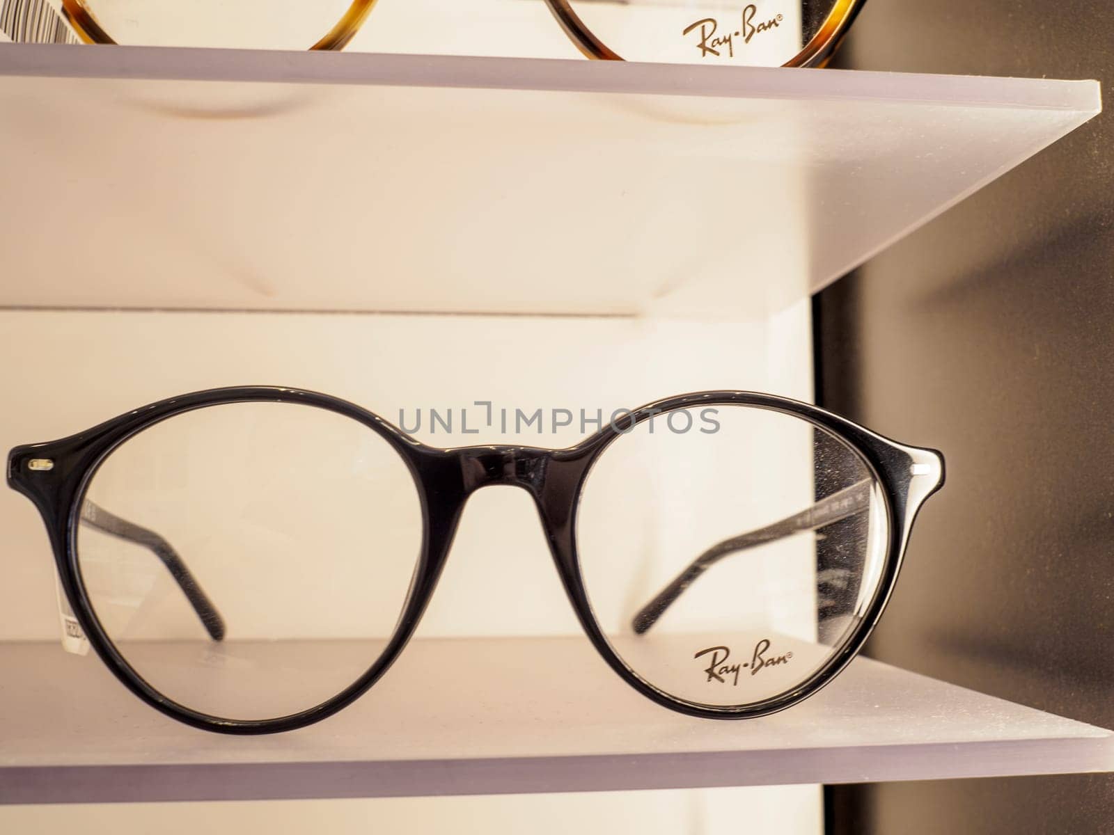 Black ray ban eyeglasses are displayed on a shelf in an optometrist shop, showcasing their style and brand recognition