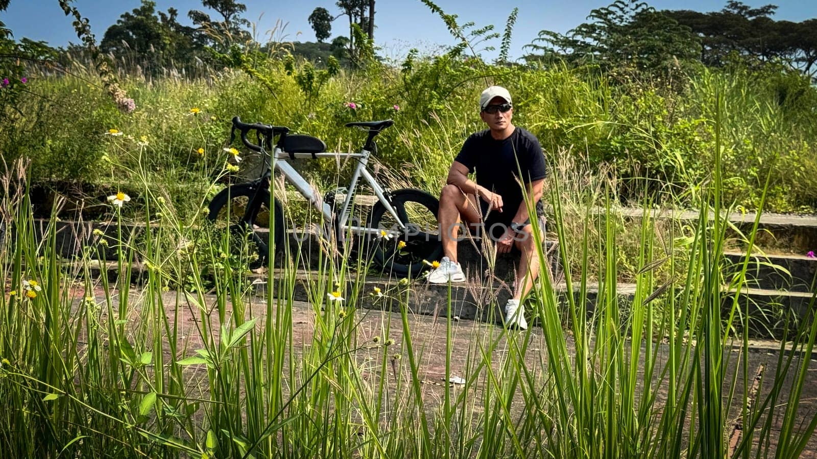 Healthy lifestyle, bicycle sport and exercise, a man in casual sportswear rides a bicycle on a sunny day surrounded by lush greenery, the image captures a sense of relaxation and outdoor adventure, good for health and sport article or content creation