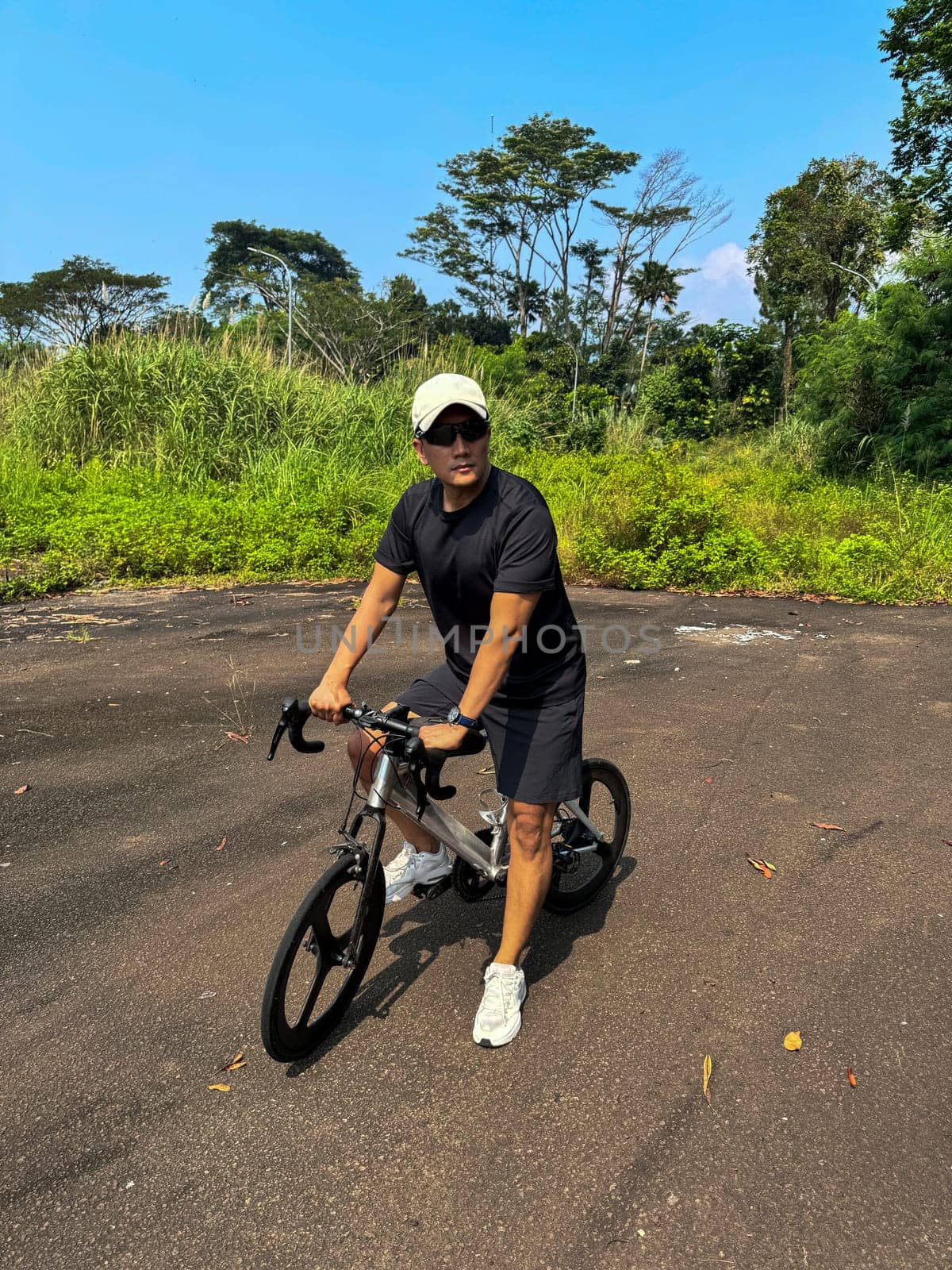 Healthy lifestyle, bicycle sport and exercise, a man in casual sportswear rides a bicycle on a sunny day surrounded by lush greenery, the image captures a sense of relaxation and outdoor adventure, good for health and sport article or content creation