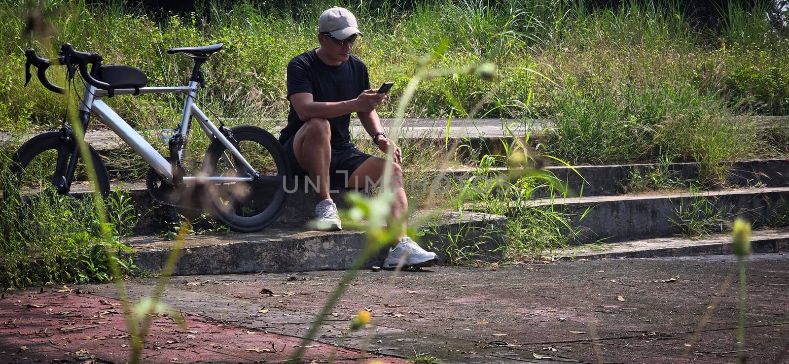 Healthy lifestyle, bicycle sport and exercise, a man in casual sportswear rides a bicycle on a sunny day surrounded by lush greenery, the image captures a sense of relaxation and outdoor adventure, good for health and sport article or content creation