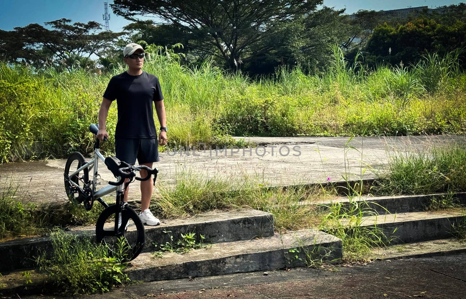 Healthy lifestyle, bicycle sport and exercise, a man in casual sportswear rides a bicycle on a sunny day surrounded by lush greenery, the image captures a sense of relaxation and outdoor adventure, good for health and sport article or content creation