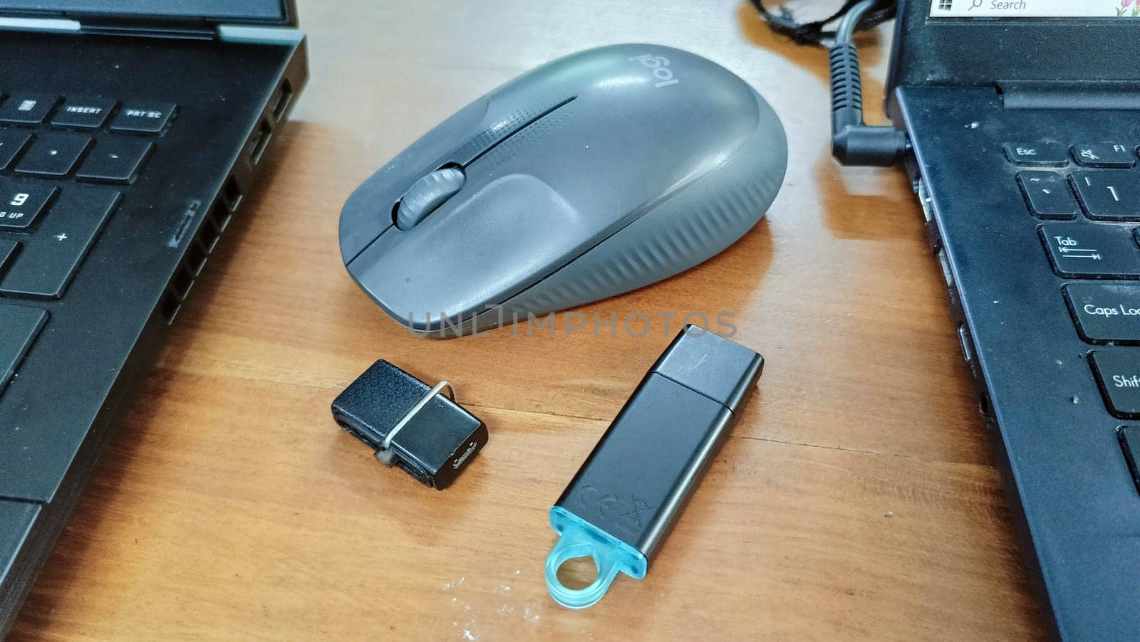 black Flashdrives and a mouse placed on a table between two laptops