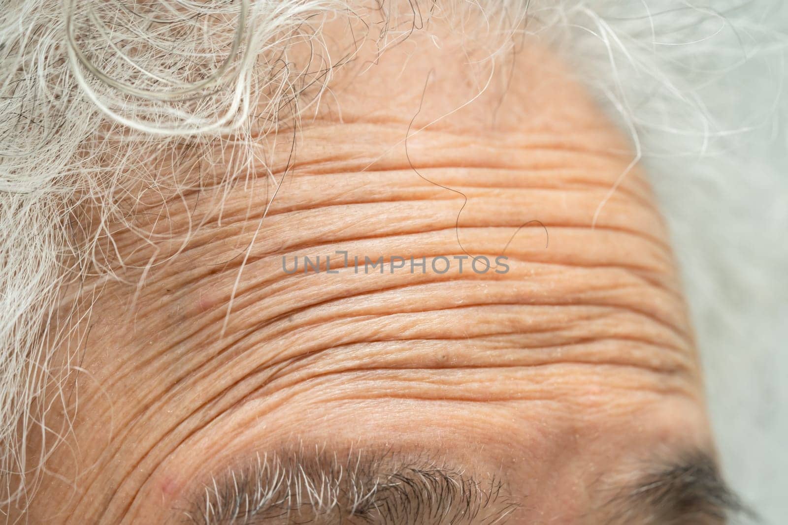 Asian elderly woman face and eye with wrinkles, portrait closeup view. by pamai