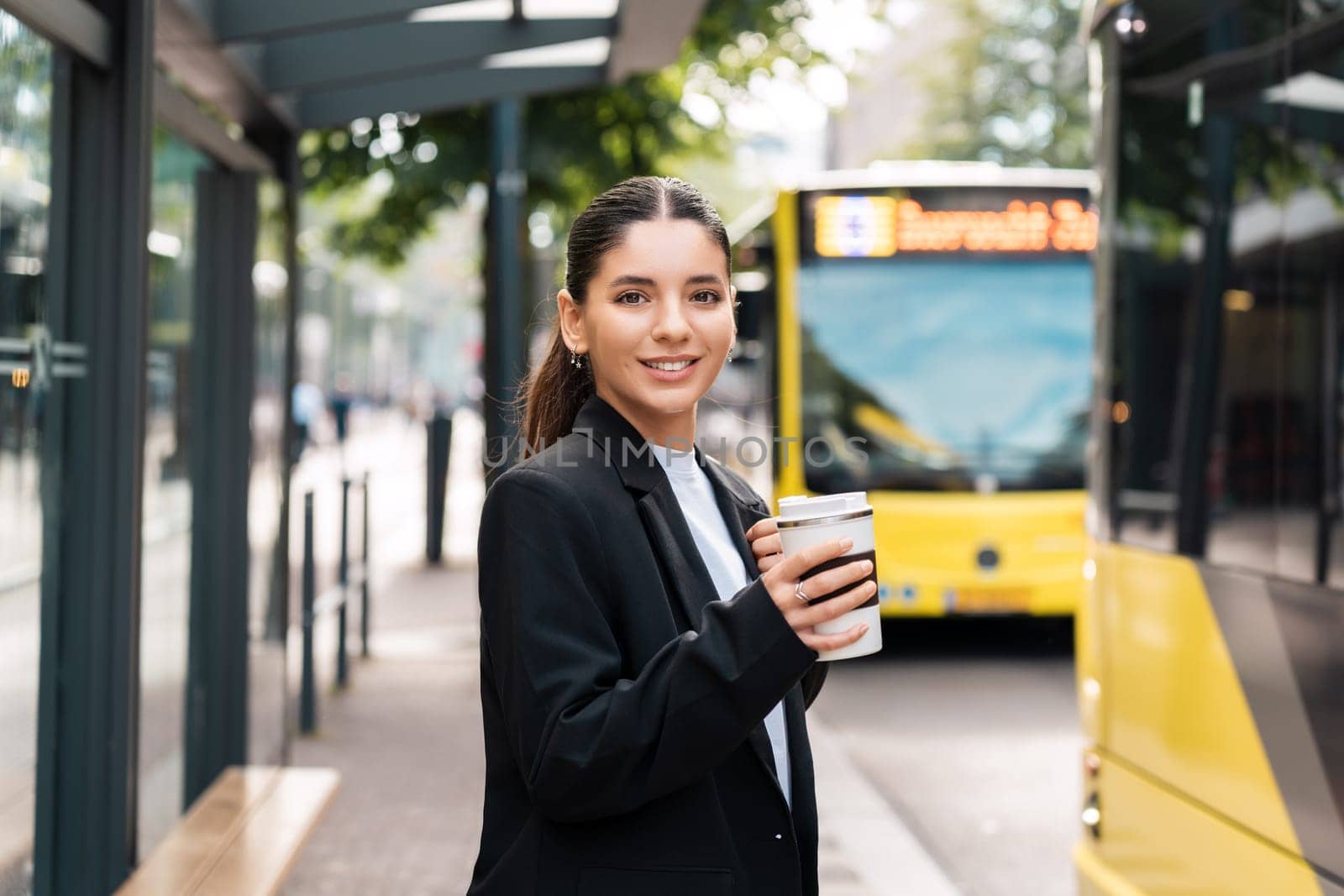 Beautiful young multiracial hispanic business woman using public transportation in city smiling and holding eco thermo cup with coffee.