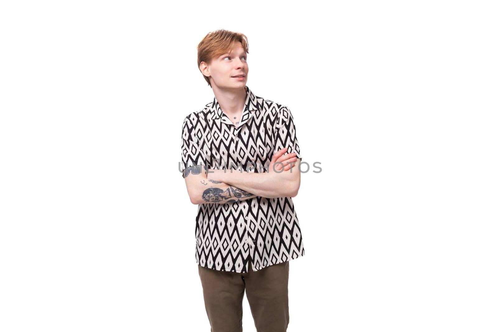 a young smart smart guy with red hair and a tattoo on his arms is dressed in a short-sleeved shirt is brainstorming.