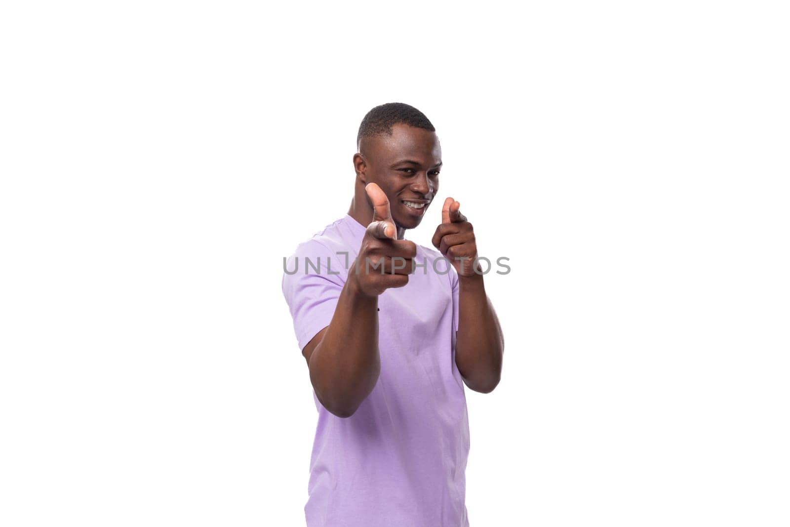 young friendly carefree american man dressed in a lilac cotton T-shirt on a white background with copy space.