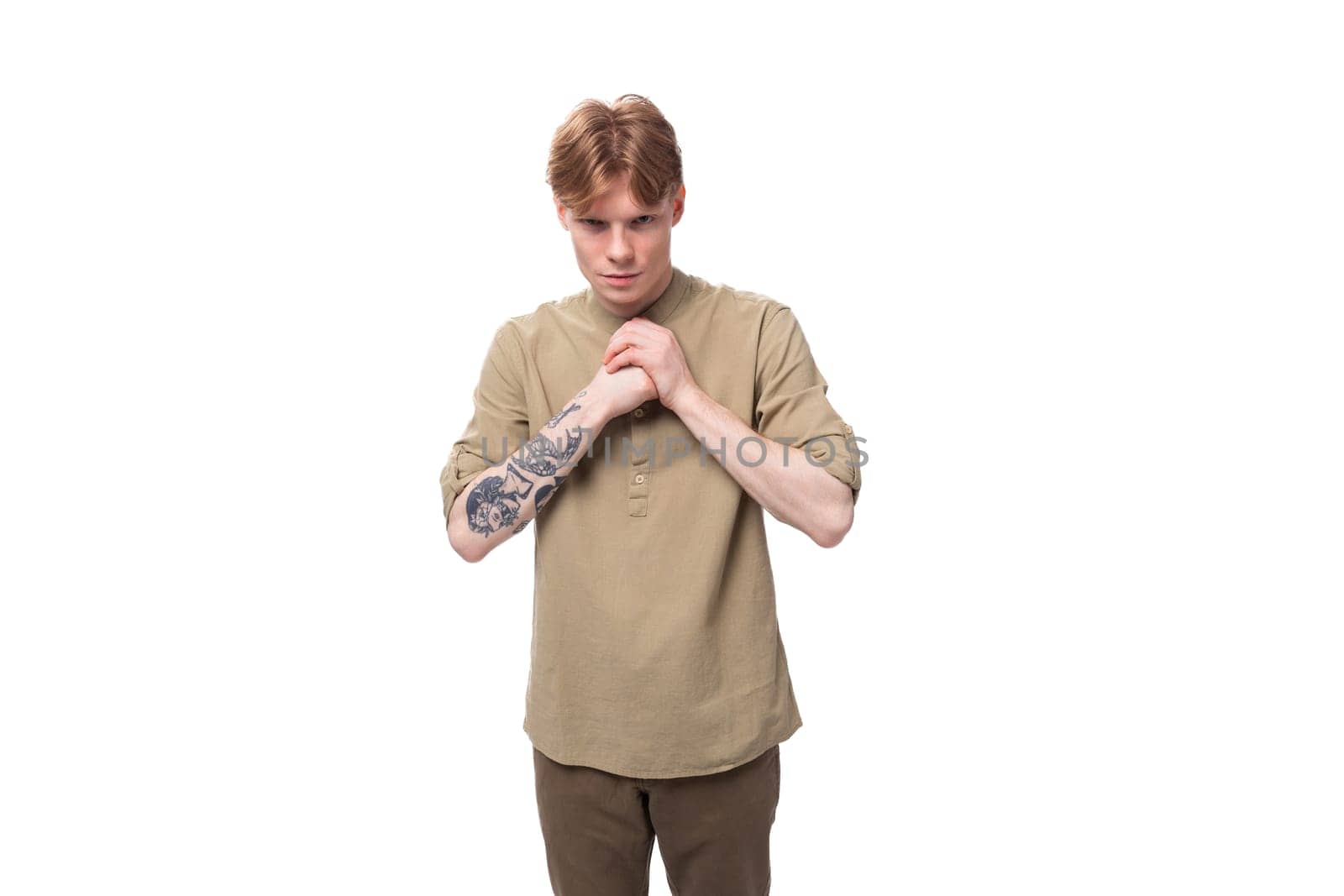 young european man with red golden hair is dressed in a light brown shirt on a white background.