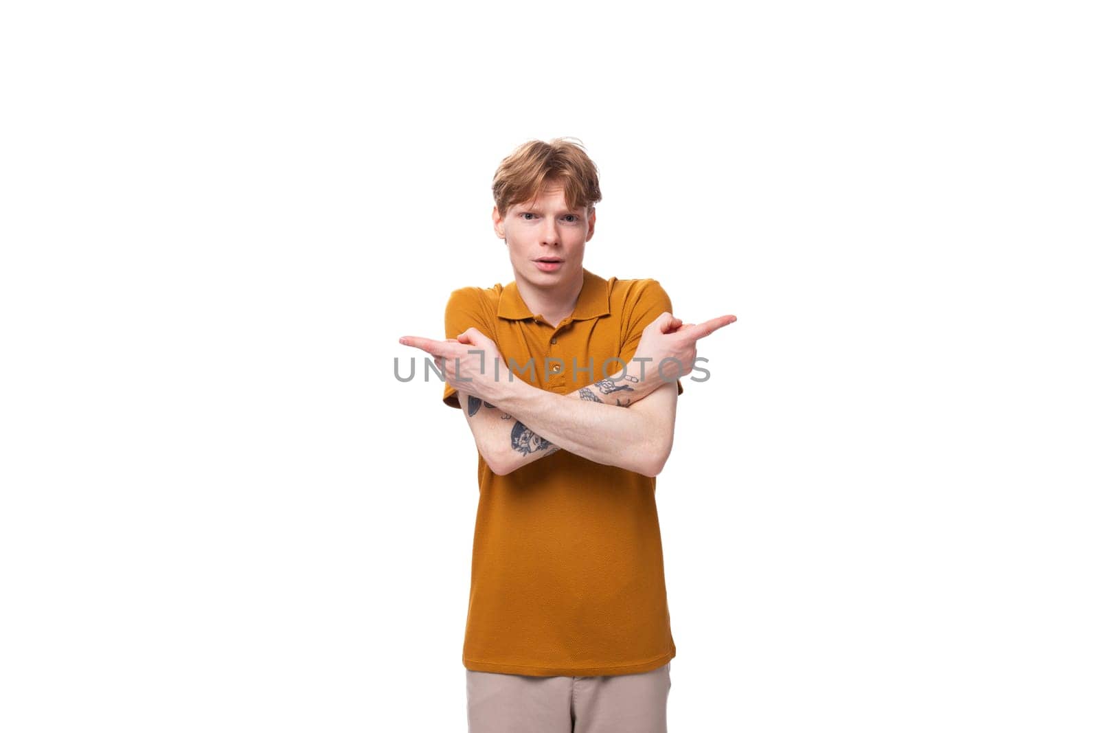 a young handsome red-haired man with a haircut and a tattoo on his arm is dressed in a summer yellow t-shirt.