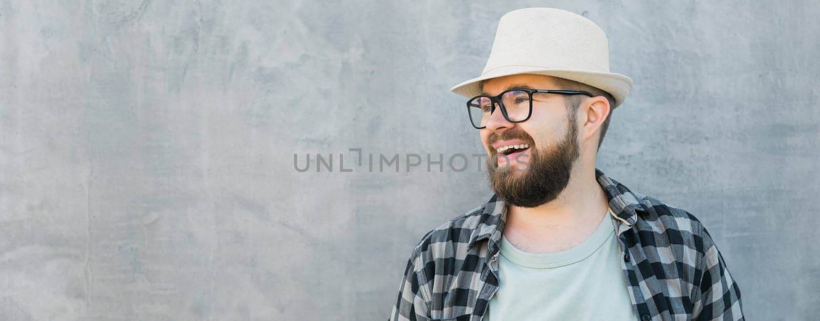 guy tourist looking happy wearing straw hat for travelling, standing against concrete wall background with copy space