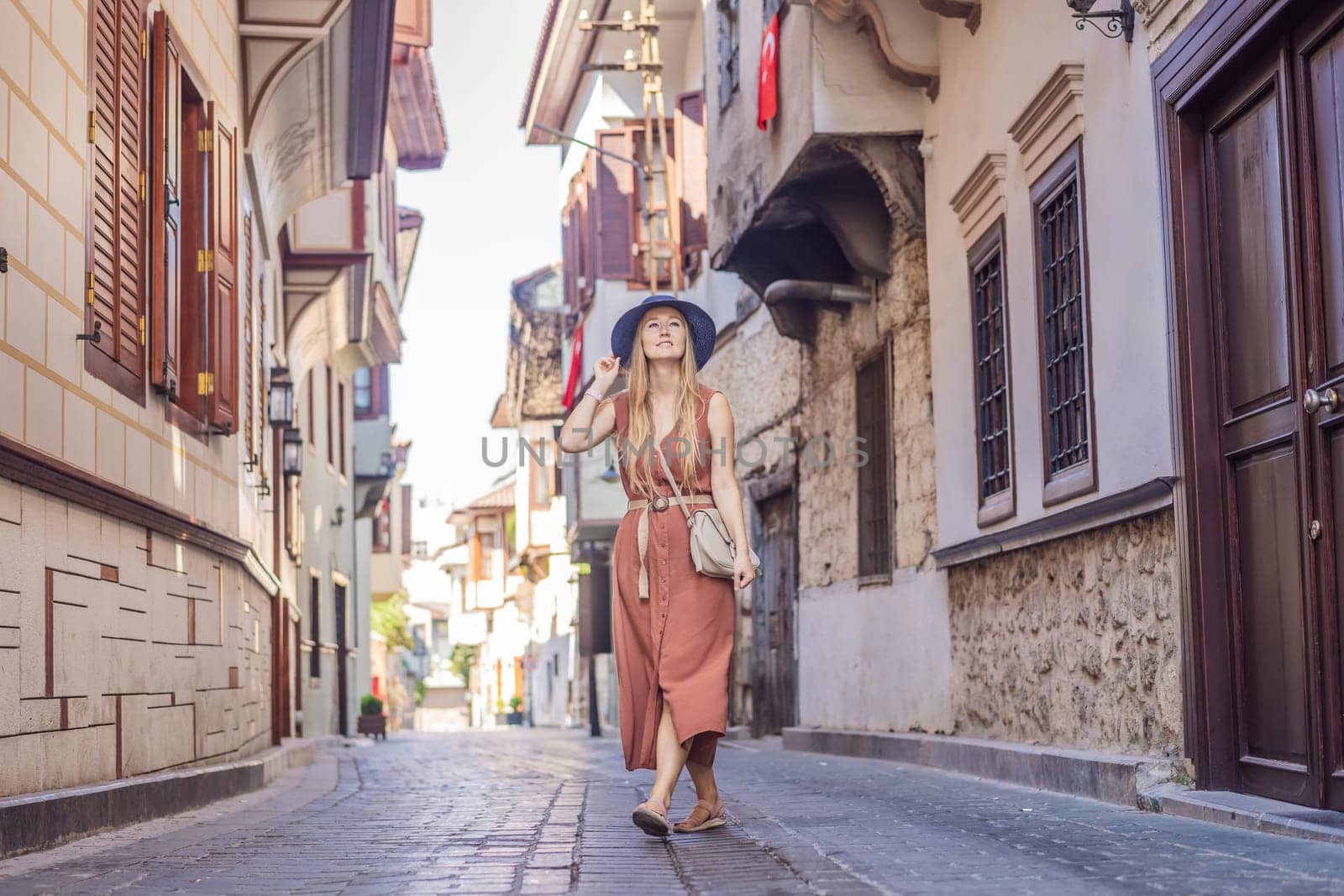 Happy woman tourist on background of old street of Antalya. female tourist traveler discover interesting places and popular attractions and walks in the old city Kalechi of Antalya, Turkey. Turkiye.