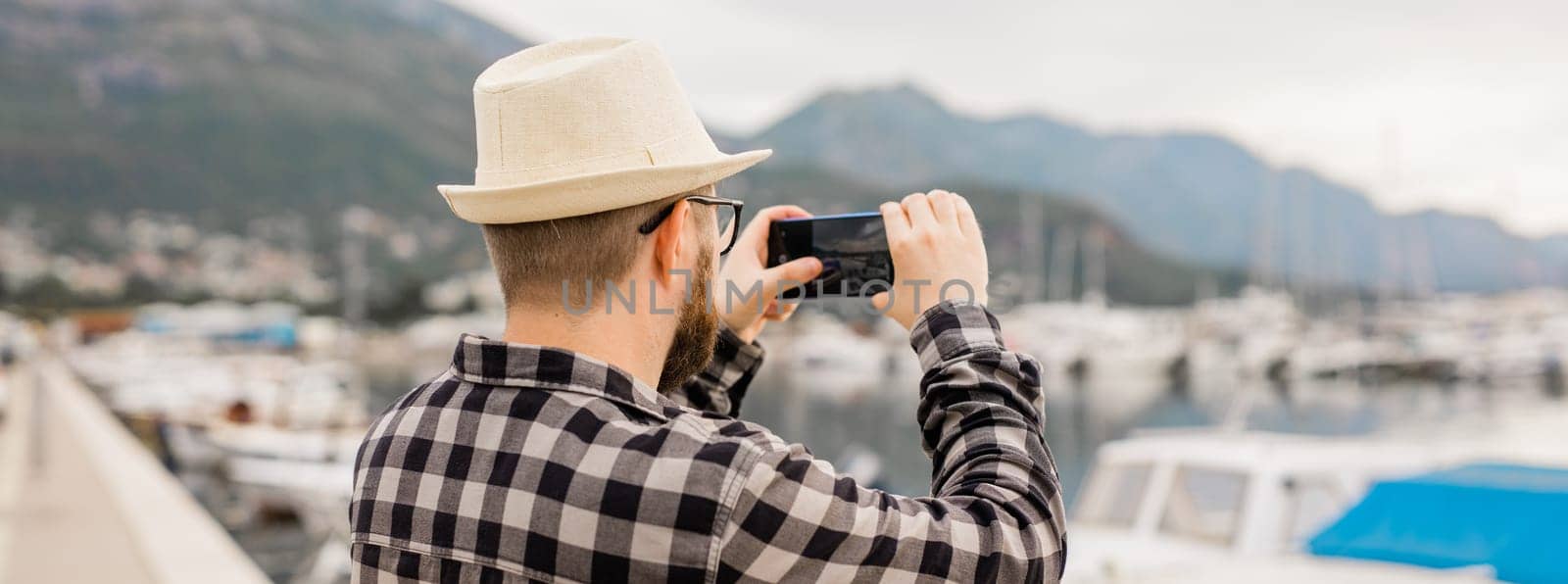 Traveller man taking pictures of luxury yachts marine during sunny day - travel and summer concept.